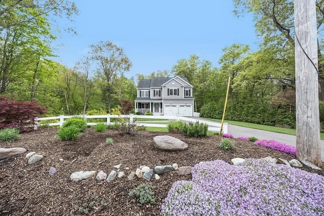 view of yard featuring a garage, fence, driveway, and a wooded view