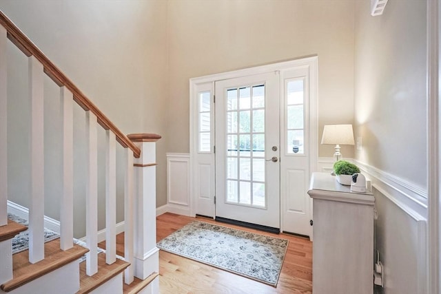 doorway to outside with stairs, a wainscoted wall, light wood-style floors, and a decorative wall