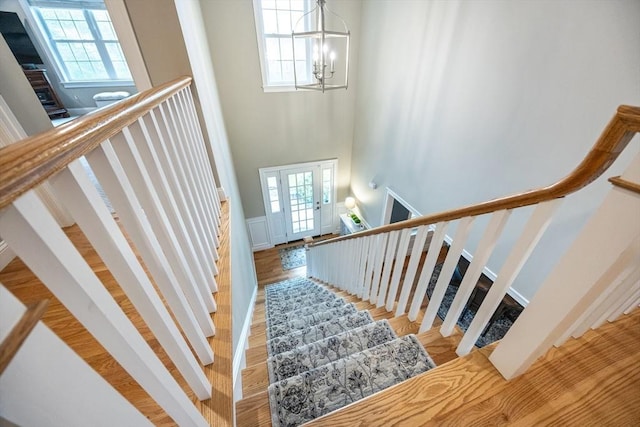 stairs featuring a chandelier, wood finished floors, and a high ceiling