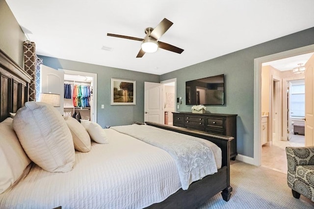 bedroom featuring a walk in closet, a closet, light colored carpet, ceiling fan, and baseboards