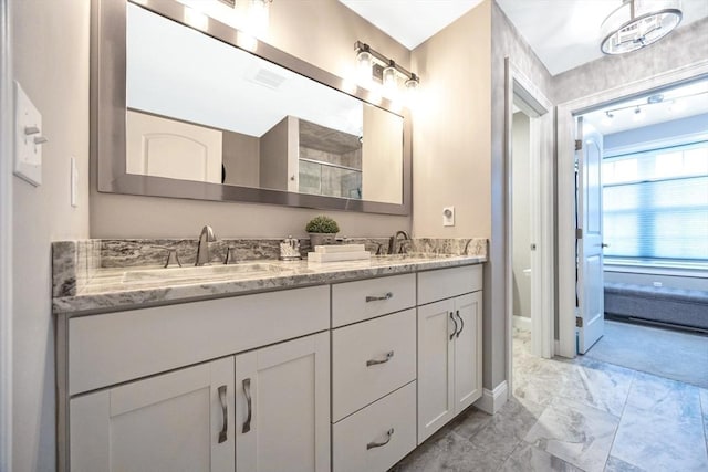 full bath featuring marble look tiles, double vanity, baseboards, and a shower