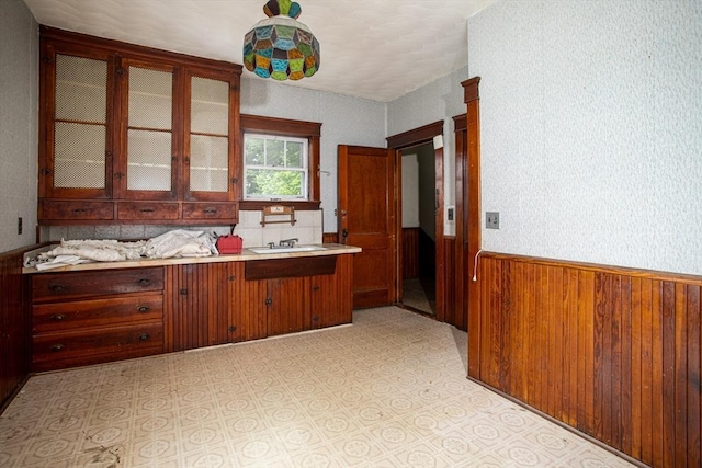 100 Weetamoe St, Fall River, MA 02720 - kitchen featuring a wainscoted wall, wooden walls, glass insert cabinets, light countertops, and light floors