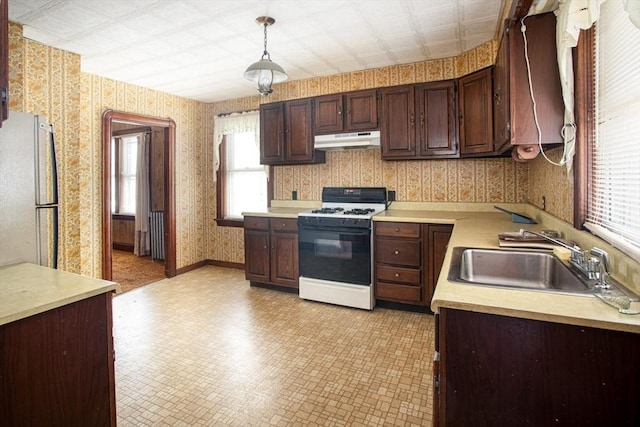 100 Weetamoe St, Fall River, MA 02720 - kitchen featuring white gas range oven, under cabinet range hood, wallpapered walls, freestanding refrigerator, and light countertops