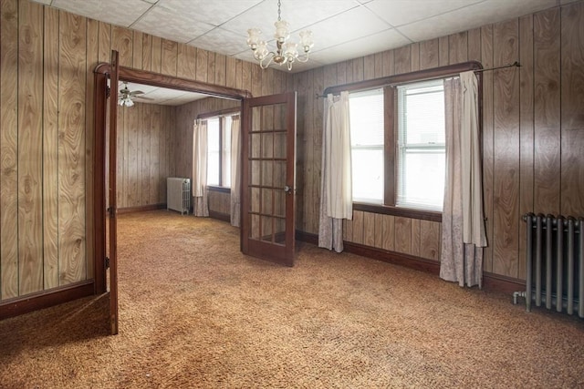 100 Weetamoe St, Fall River, MA 02720 - carpeted empty room featuring radiator heating unit, a chandelier, french doors, and wood walls