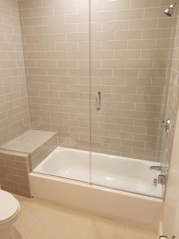 bathroom with enclosed tub / shower combo, toilet, and tile flooring