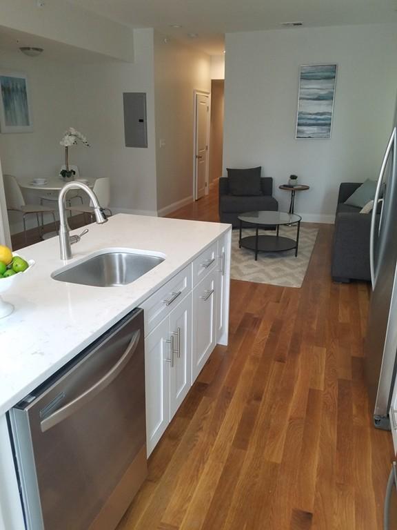 kitchen featuring light stone countertops, white cabinetry, appliances with stainless steel finishes, sink, and hardwood / wood-style flooring