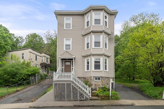 view of property with aphalt driveway and fence