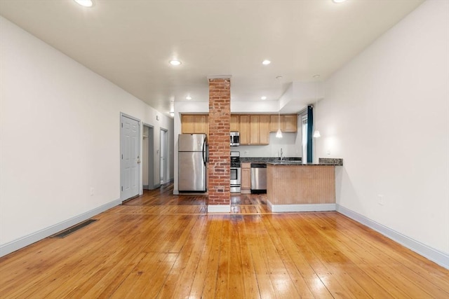 kitchen featuring a sink, visible vents, light wood finished floors, baseboards, and appliances with stainless steel finishes