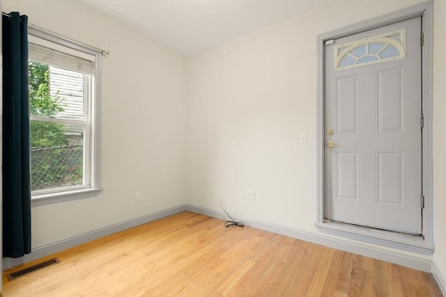 unfurnished room featuring plenty of natural light, visible vents, baseboards, and light wood-type flooring