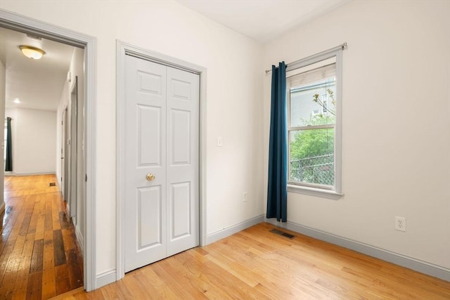 unfurnished bedroom with baseboards, light wood finished floors, and visible vents