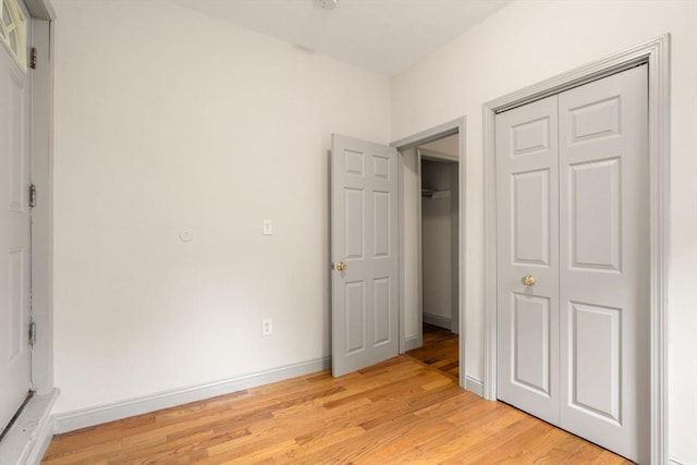 unfurnished bedroom with a closet, baseboards, and light wood-style floors