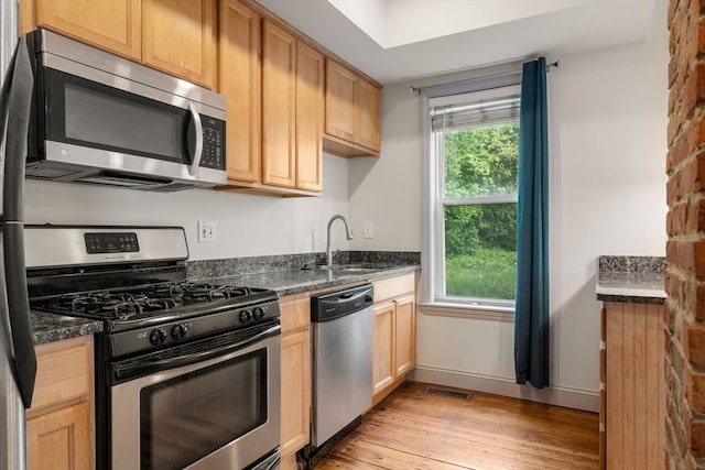 kitchen featuring light wood-style flooring, a sink, visible vents, baseboards, and appliances with stainless steel finishes