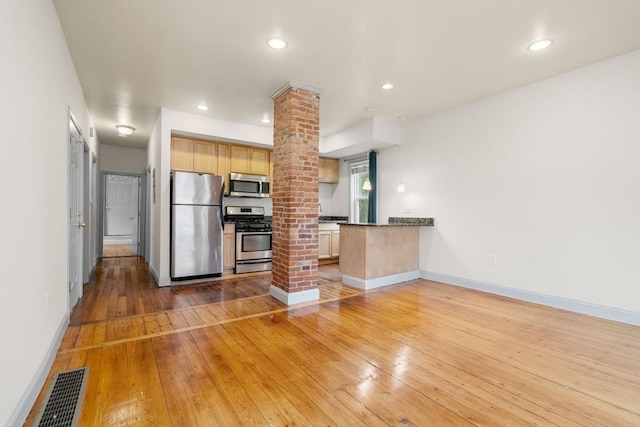 kitchen featuring visible vents, decorative columns, a peninsula, hardwood / wood-style flooring, and stainless steel appliances