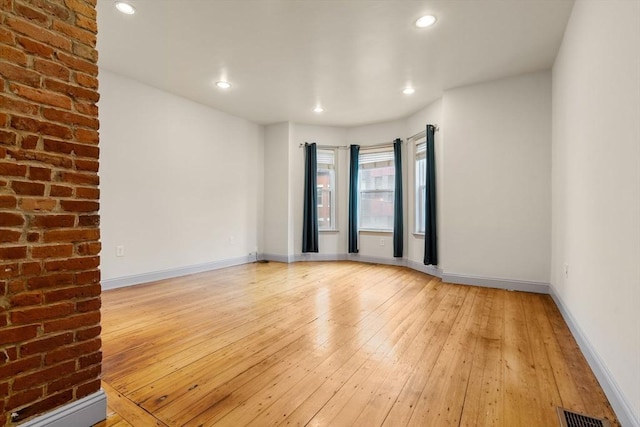 empty room with baseboards, light wood-type flooring, visible vents, and recessed lighting
