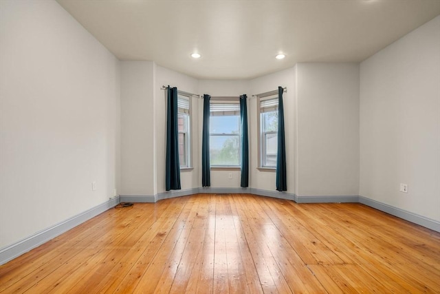 unfurnished room featuring light wood finished floors, baseboards, and recessed lighting