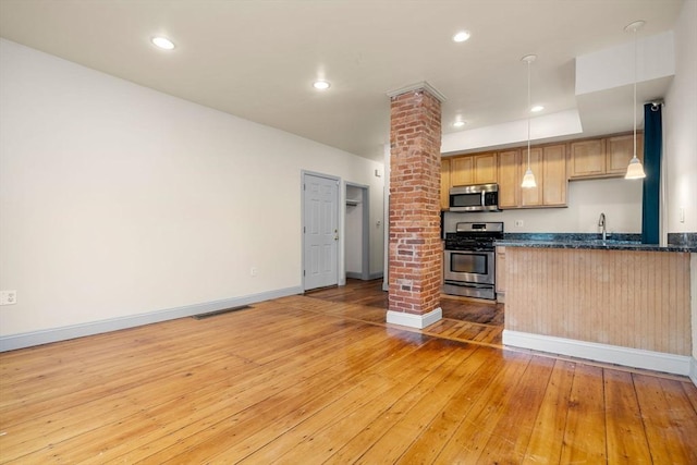 kitchen featuring visible vents, a sink, decorative columns, stainless steel appliances, and light wood-type flooring