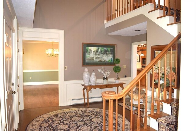 1820 Milk St, Dighton, MA 02715 - foyer with a baseboard radiator, dark wood-type flooring, stairs, a chandelier, and a wainscoted wall
