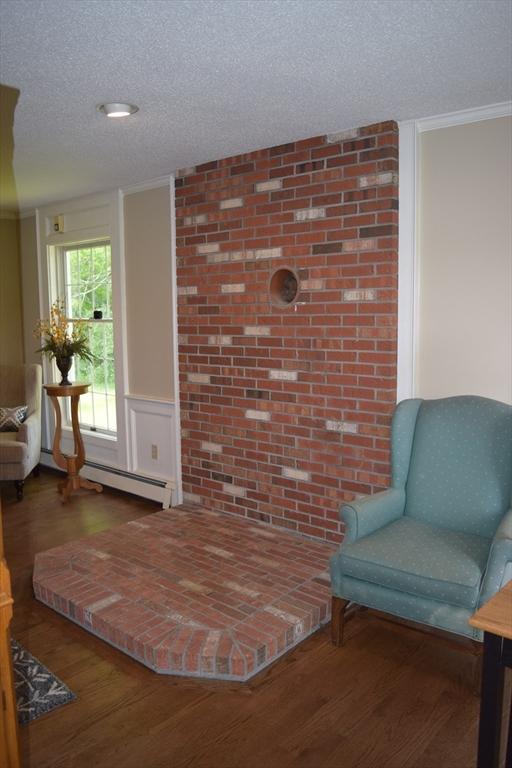 1820 Milk St, Dighton, MA 02715 - sitting room with a textured ceiling, wood finished floors, a baseboard heating unit, and brick wall