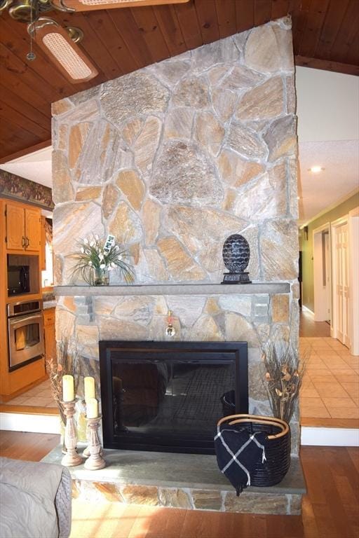1820 Milk St, Dighton, MA 02715 - detailed view of stainless steel oven, a stone fireplace, wooden ceiling, black microwave, and wood finished floors