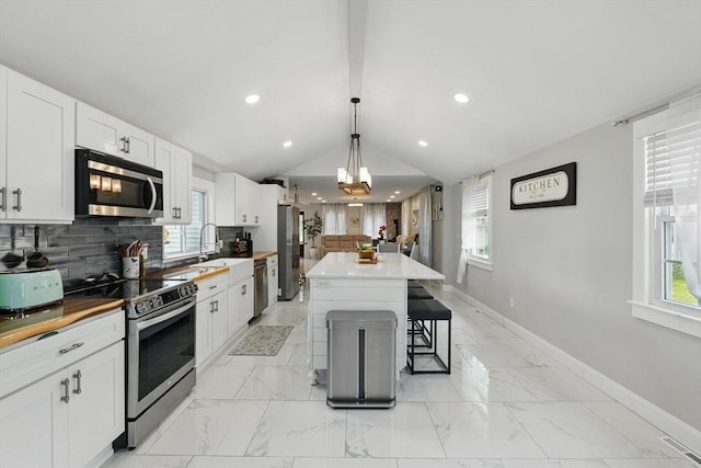 399 N Main St, Salem, NH 03079 - kitchen featuring stainless steel appliances, decorative backsplash, a breakfast bar area, white cabinets, and vaulted ceiling