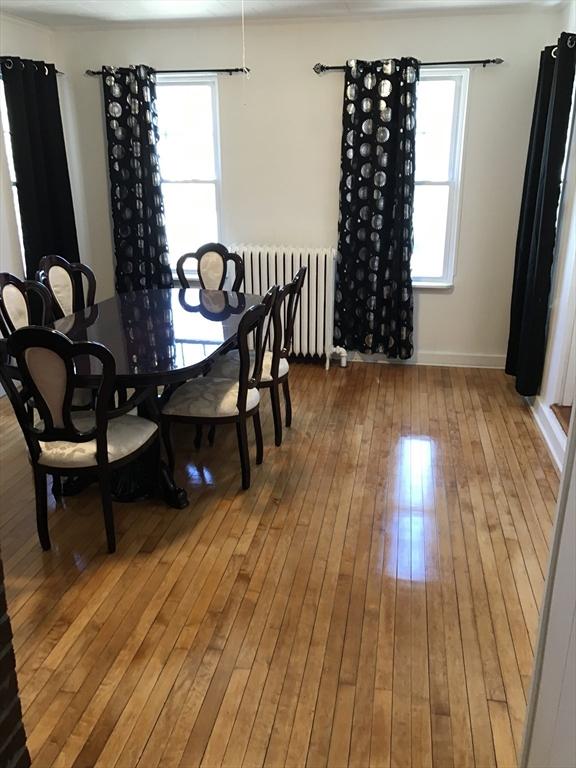 dining space featuring radiator heating unit, baseboards, wood-type flooring, and a wealth of natural light