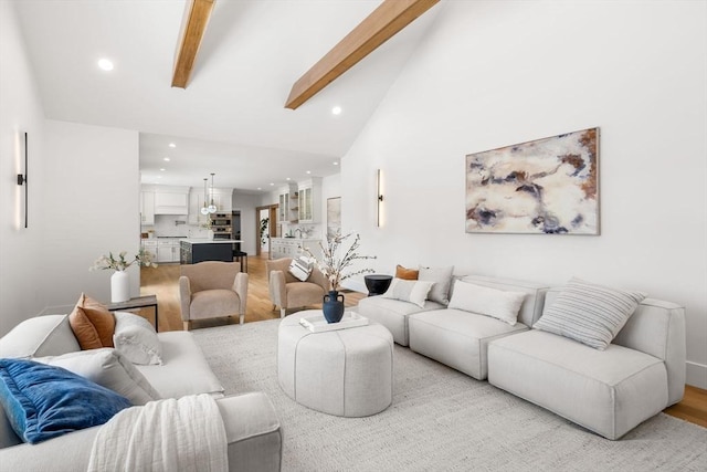 living room featuring beamed ceiling, high vaulted ceiling, and light wood-type flooring