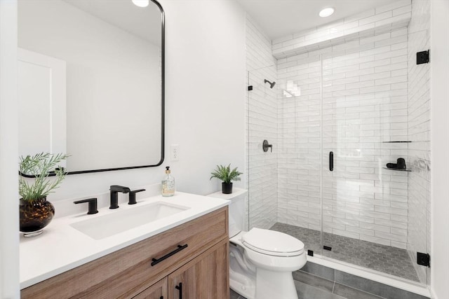 bathroom with a shower with door, vanity, and toilet