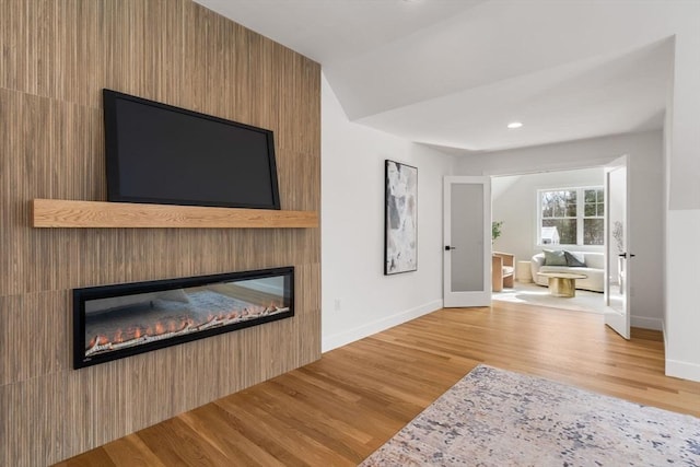 living room featuring light hardwood / wood-style flooring, a large fireplace, and french doors