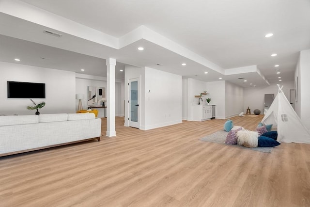 playroom featuring light hardwood / wood-style floors and decorative columns