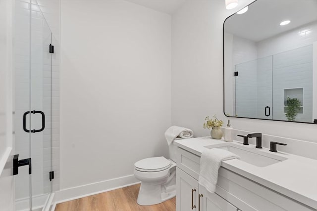 bathroom featuring vanity, toilet, a shower with shower door, and hardwood / wood-style floors