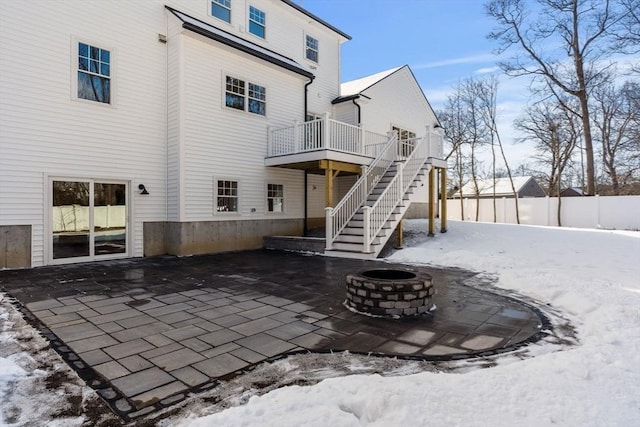 snow covered back of property featuring a fire pit