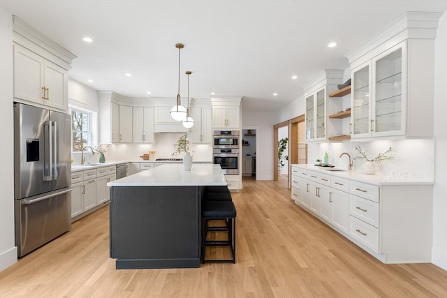 kitchen featuring pendant lighting, white cabinetry, stainless steel appliances, a kitchen breakfast bar, and a kitchen island