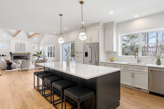 kitchen featuring stainless steel appliances, white cabinetry, hanging light fixtures, and sink