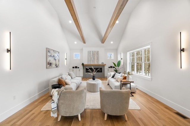 living room featuring beam ceiling, high vaulted ceiling, and light hardwood / wood-style floors