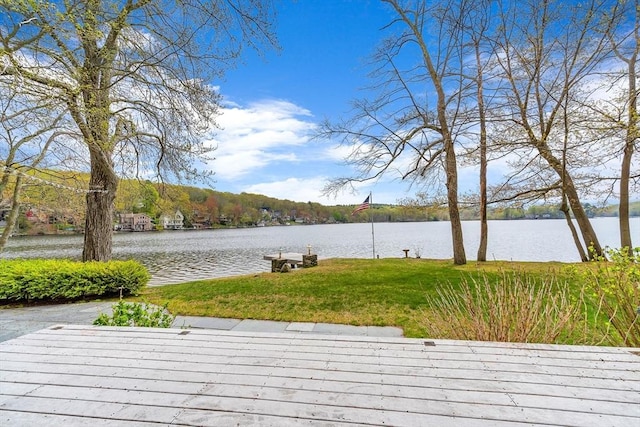 wooden terrace featuring a water view and a lawn