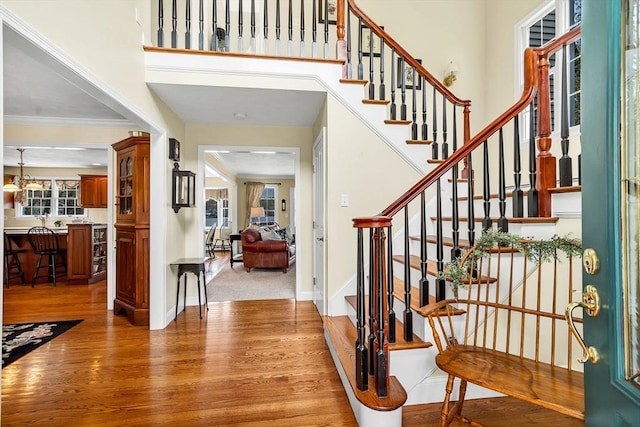 entryway with light wood finished floors, stairs, baseboards, and crown molding