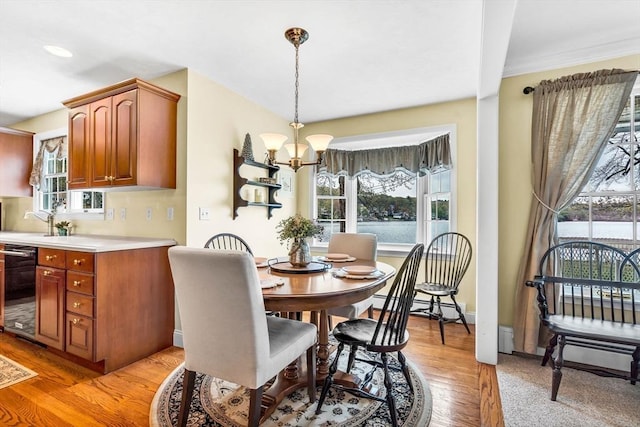dining space with a chandelier, healthy amount of natural light, light wood finished floors, and baseboards