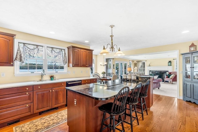kitchen featuring a kitchen breakfast bar, light wood finished floors, open floor plan, hanging light fixtures, and a sink