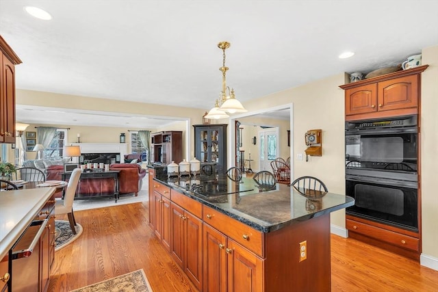 kitchen with black appliances, light wood-style flooring, a kitchen island, decorative light fixtures, and recessed lighting