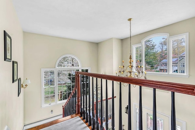 corridor featuring a baseboard radiator, a chandelier, an upstairs landing, and healthy amount of natural light