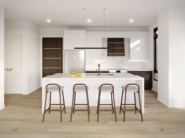 kitchen with light hardwood / wood-style flooring, sink, an island with sink, and high end refrigerator