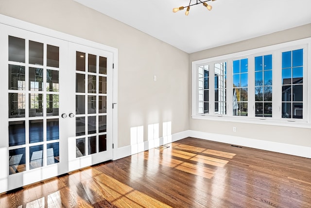 spare room featuring a chandelier and hardwood / wood-style floors