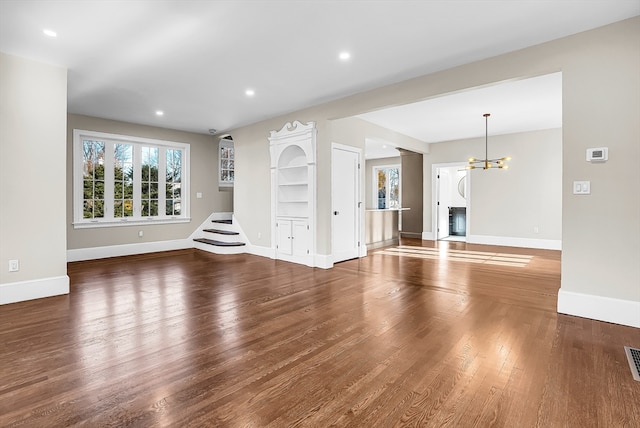 unfurnished living room with dark hardwood / wood-style floors and an inviting chandelier