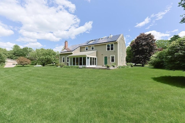 15 Amys Way, Franklin, MA 02038 - rear view of house featuring a sunroom, a chimney, roof mounted solar panels, and a yard