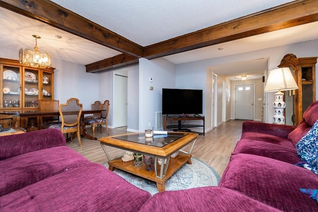 living room with light wood-type flooring, an inviting chandelier, and beam ceiling