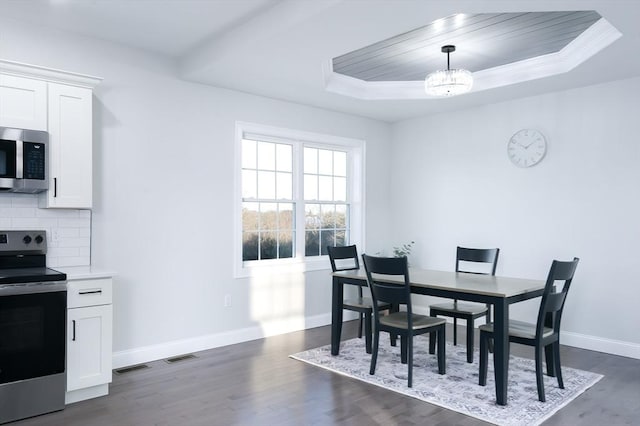 dining space featuring baseboards, visible vents, a raised ceiling, dark wood-type flooring, and a chandelier