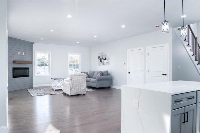 living room with a large fireplace, stairs, wood finished floors, and recessed lighting