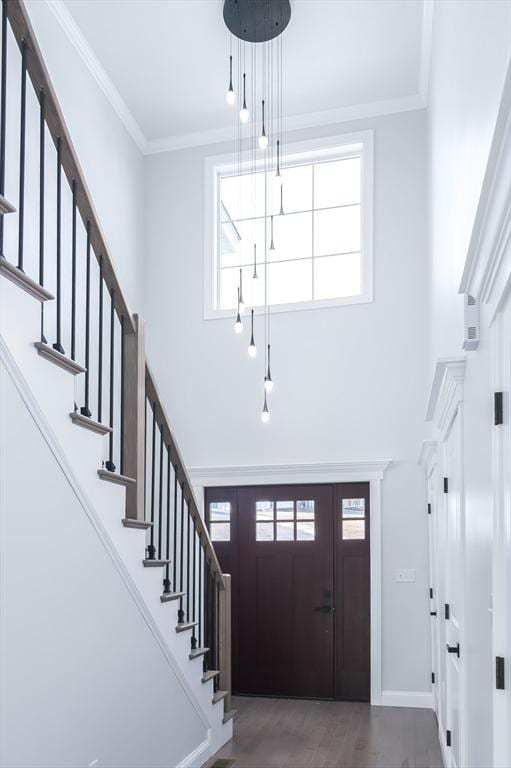 foyer entrance with crown molding, a towering ceiling, baseboards, and stairs