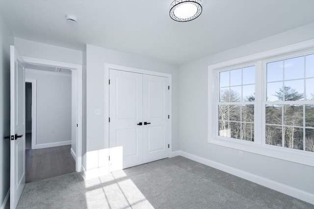 unfurnished bedroom with attic access, a closet, carpet flooring, and baseboards