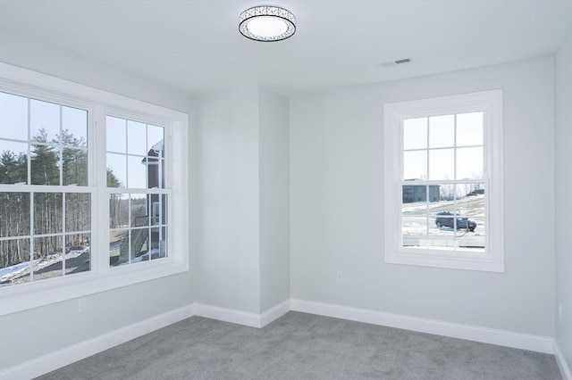 carpeted spare room featuring visible vents and baseboards